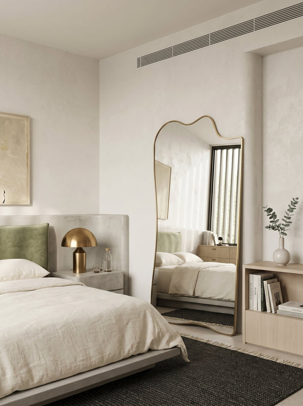 Champagne gold asymmetrical full-length leaner mirror in a minimalist bedroom