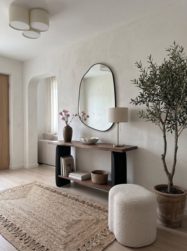 Matte black asymmetrical wall mirror above a console in a calm entryway