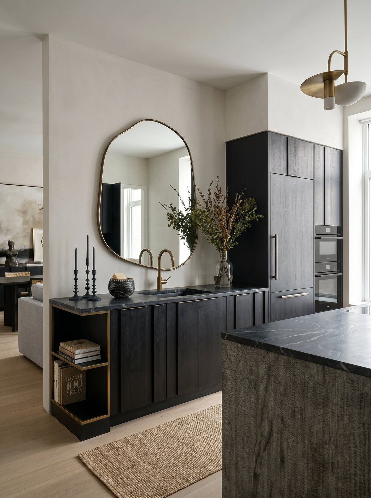 Champagne gold asymmetrical mirror above a black kitchen counter with a brass tap