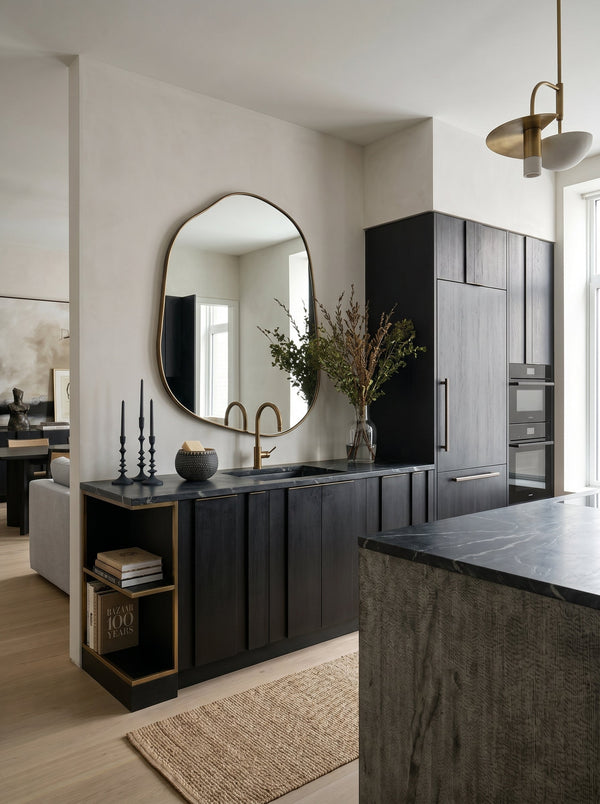 Champagne gold asymmetrical mirror above a black kitchen counter with a brass tap